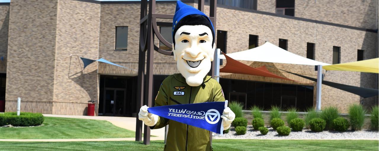 Jax mascot holding GVSU flag in front of Jackson College clock tower